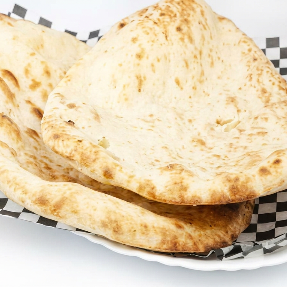 Stack of golden-brown flatbreads served on black-and-white checkered paper in a white plate.